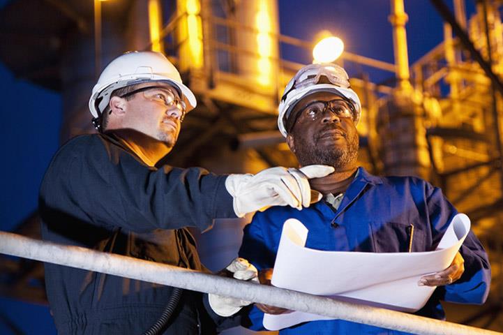 An Image of two plant workers standing outside a facility viewing plans.