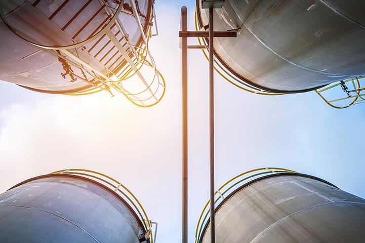 ground to sky view from the middle of four storage tanks